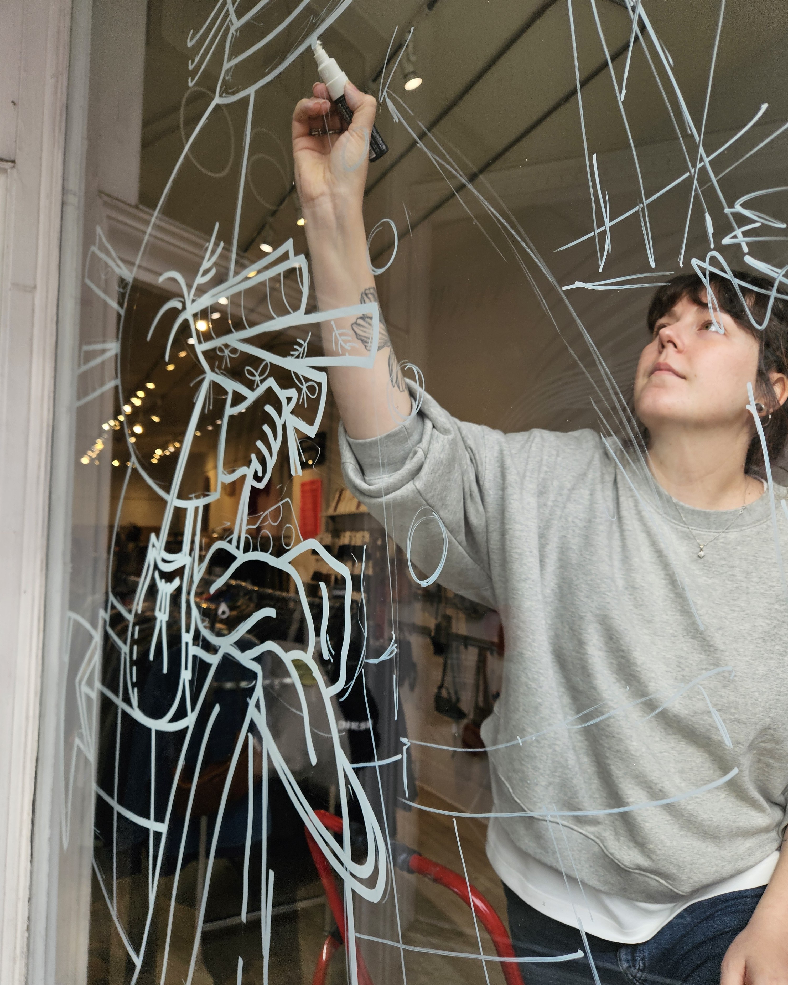 Window wonderland artist drawing on a shop's window with a white marker