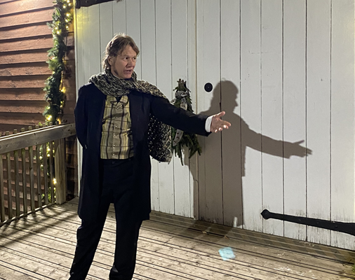 A person in clothes from the 1800s with festive lights.