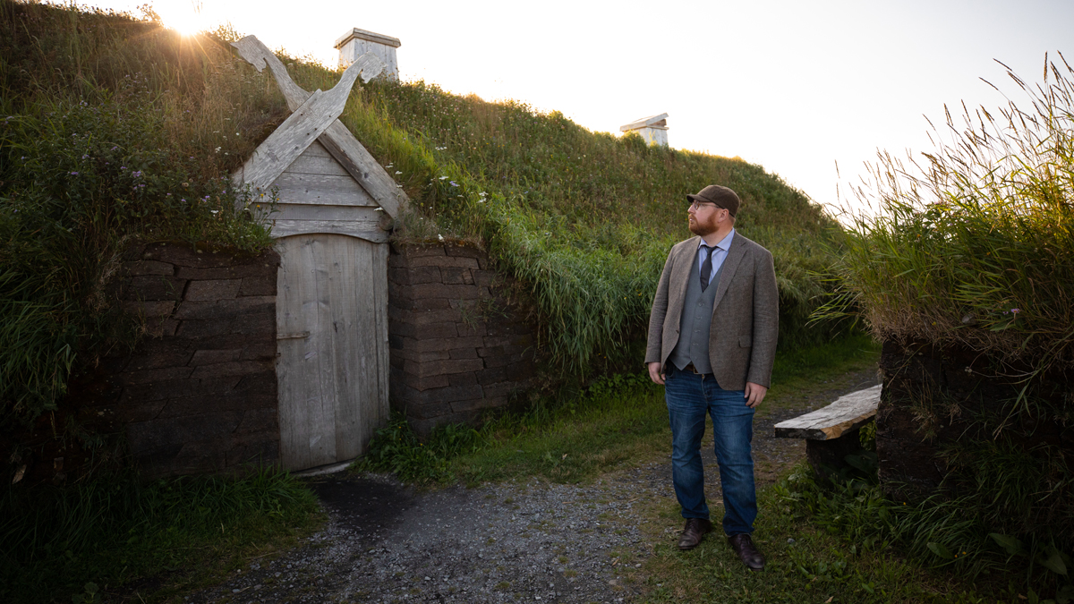 Man standing in front of wooden doorway with green grass roof