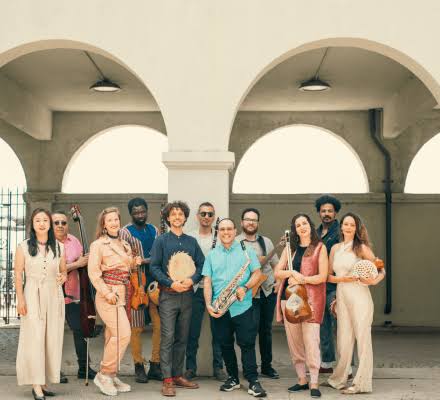 A group of musicians stand under an archway.