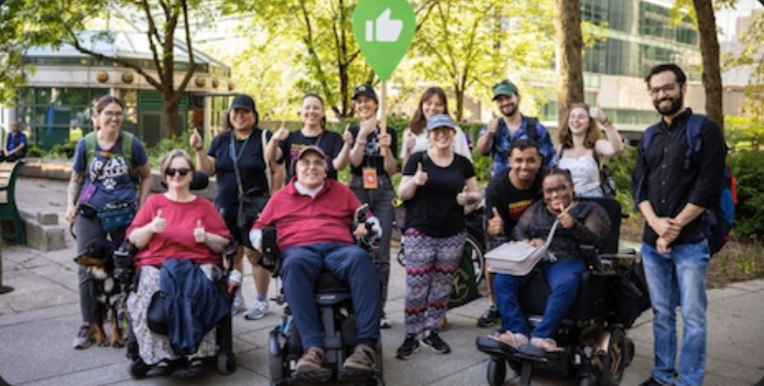 Group of people smiling both standing and wheelchairs.