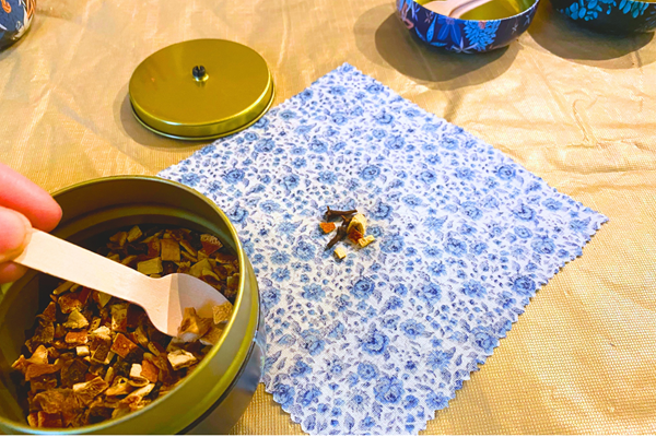 A spoon placing potpourri into a cloth holder.