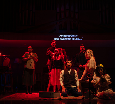 Children on a dark stage singing.