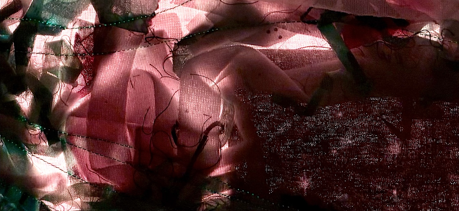 Detail of illuminated textile map in shades of dark pink