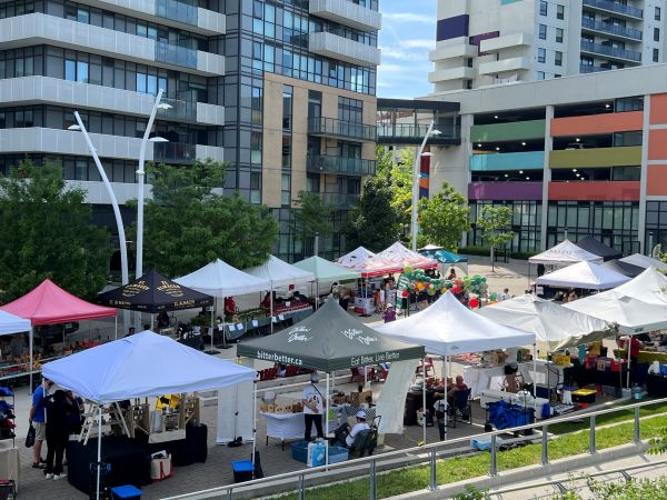 famers' market set up with tents in a square surrounded by apartment buildings.