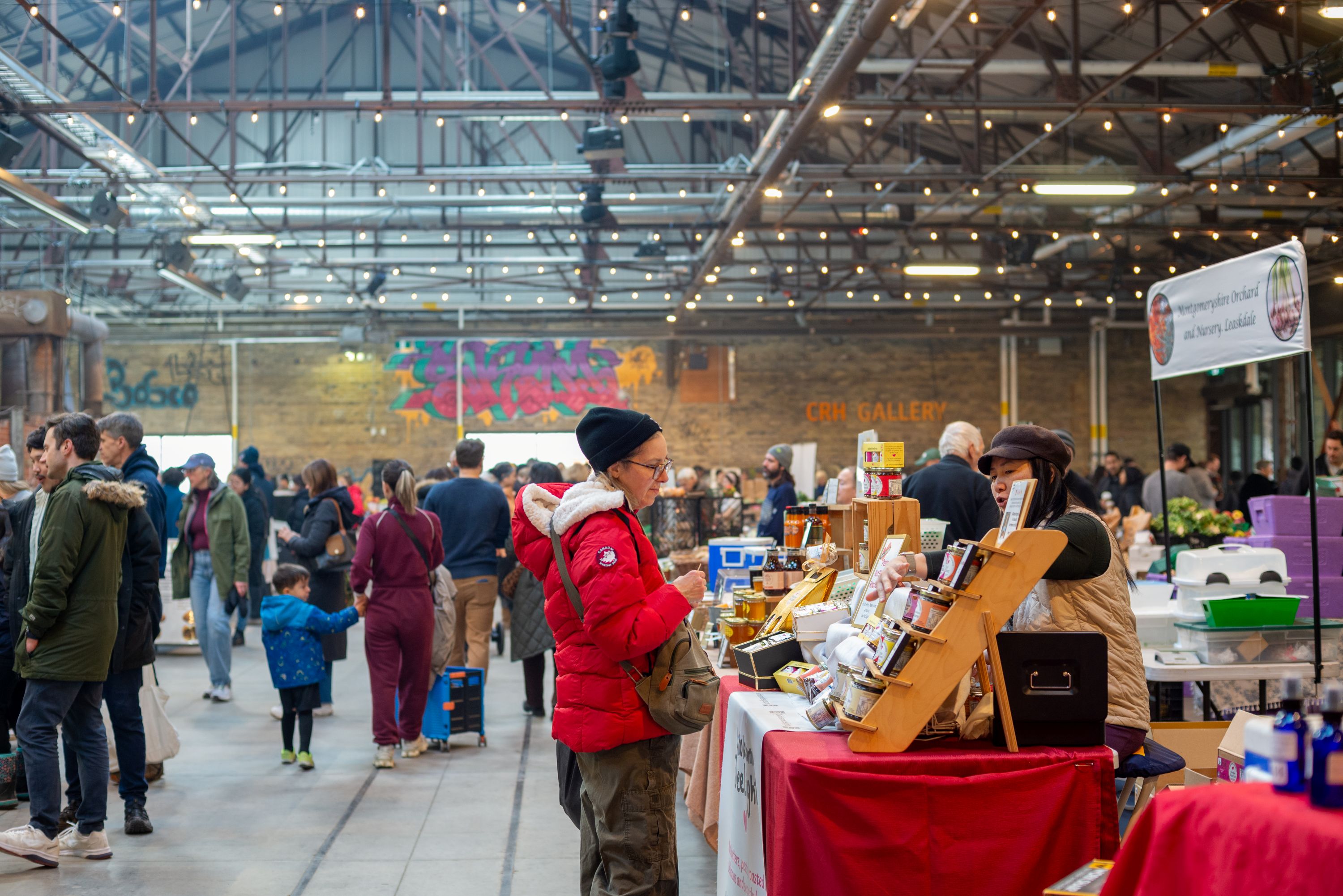 Shoppers at the indoor farmers market engaging with vendors.