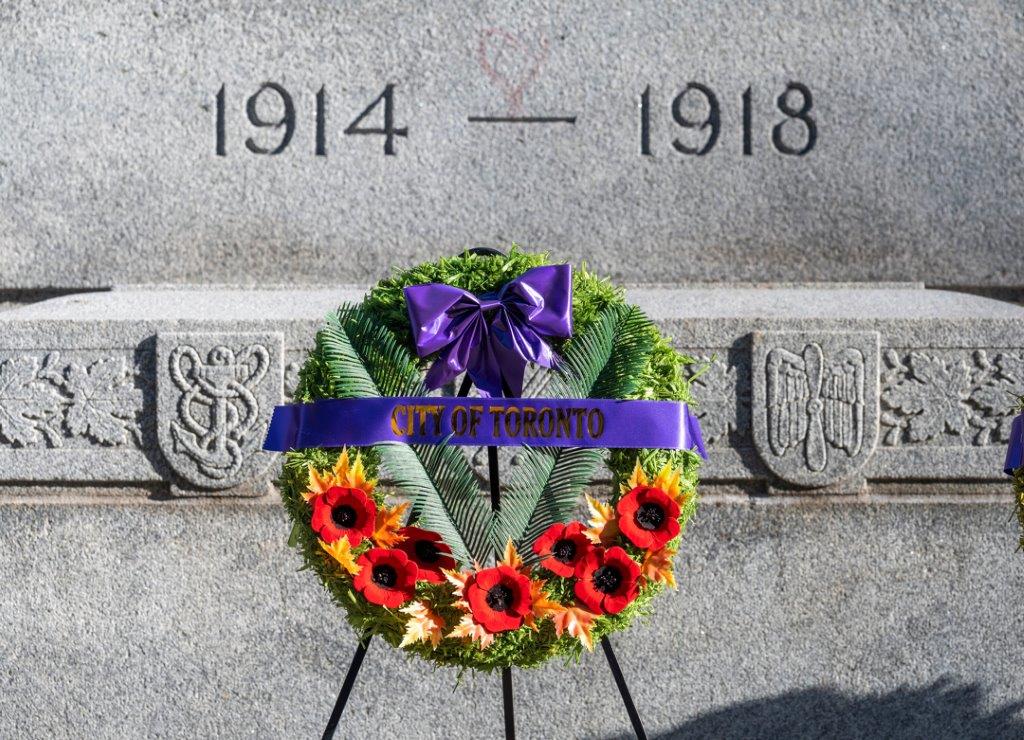 A Poppy wreath with a City of Toronto ribbon, in front of a cenotaph