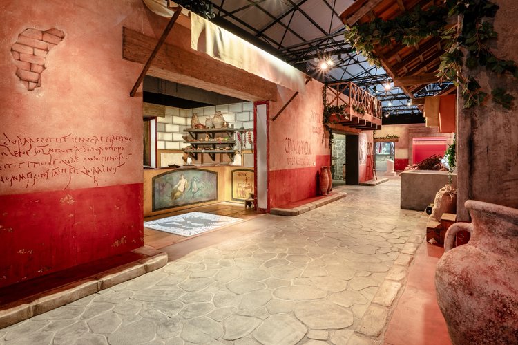 A reconstructed pre-eruption Pompeian street marketplace, with colourful walls, fountains and ancient graffiti.