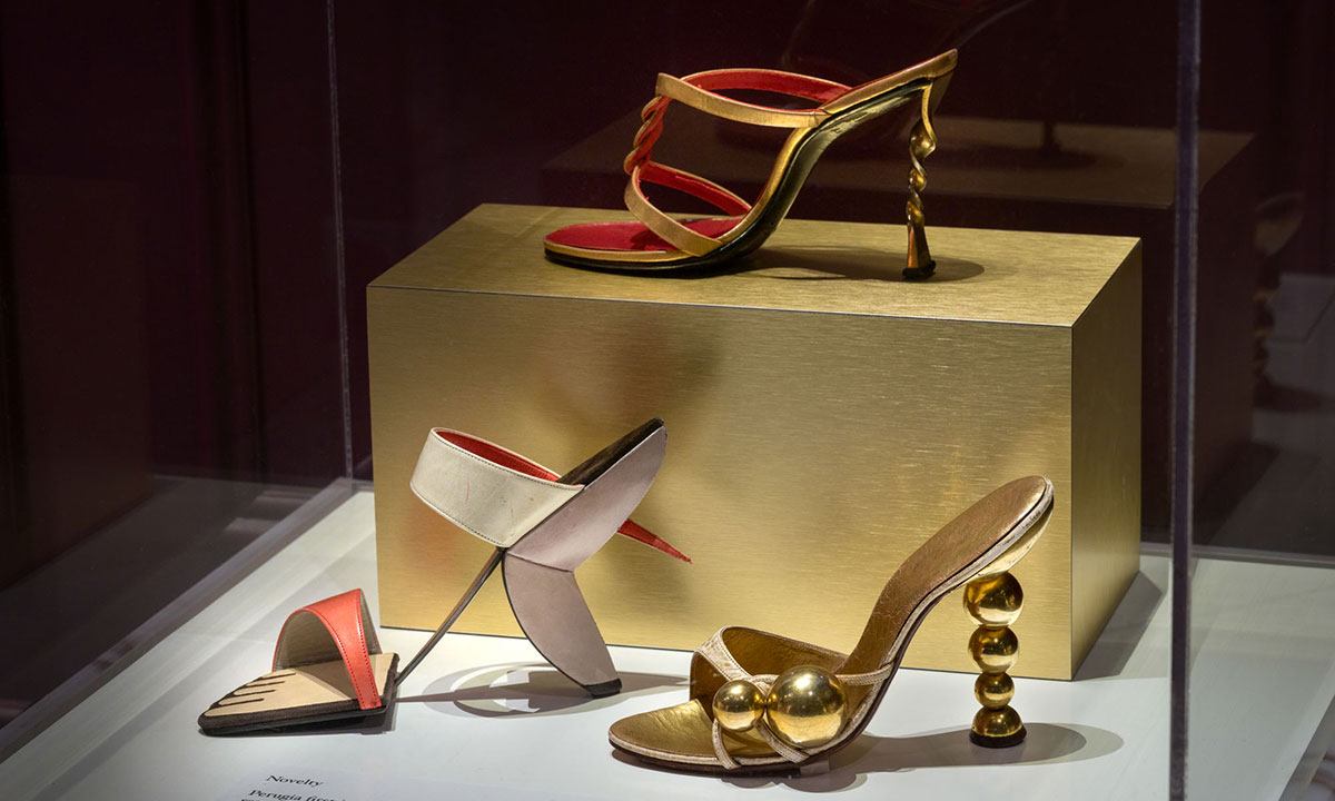 Three singular shoes with novelty heels in a glass display case.