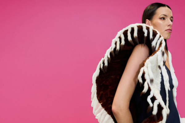 Model wearing a black and white dress by Randi Nelson, against a pink background