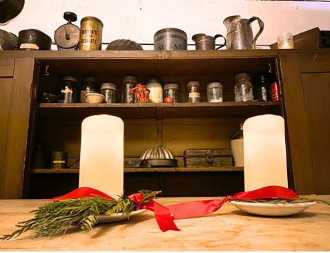 Two candles on a table in an old kitchen.