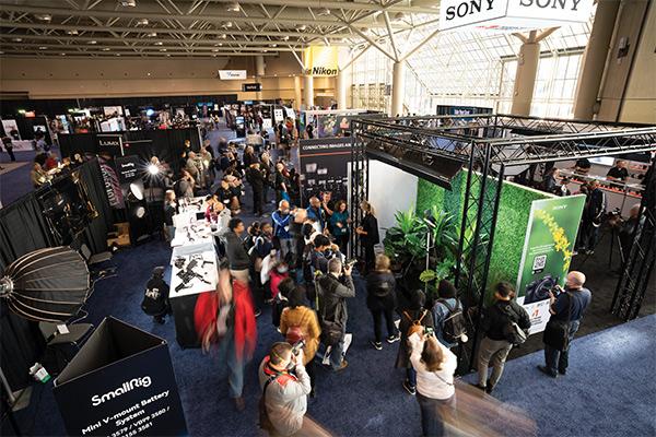 A group of people gather around multiple vendors and information booths to watch product demonstrations.