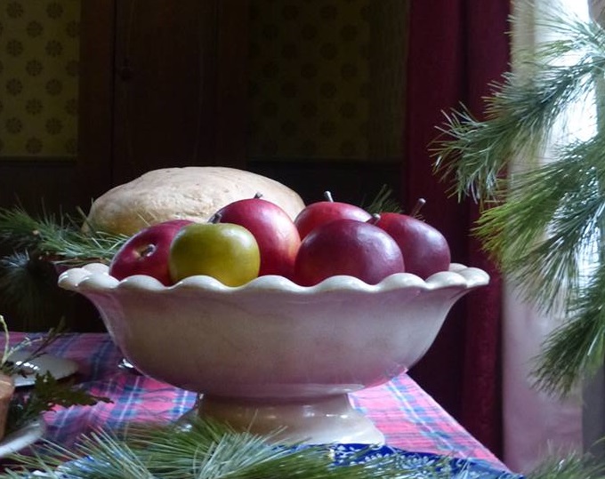 Apples in bowl next to cedar and pine boughs
