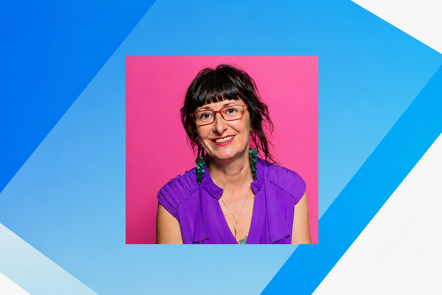 A smiling woman with dark hair, red glasses and a purple top against a pink and blue geometric background.