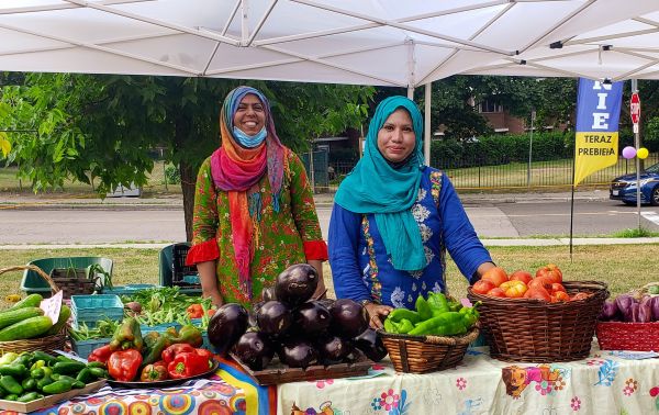 table with fresh locally grown produce and two women vendors.