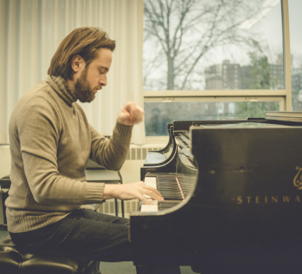 Daniil Trifonov plays the piano. He wears a moss green turtleneck.
