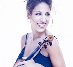 Leticia Moreno looks over her shoulder. She holds her violin in her hand.