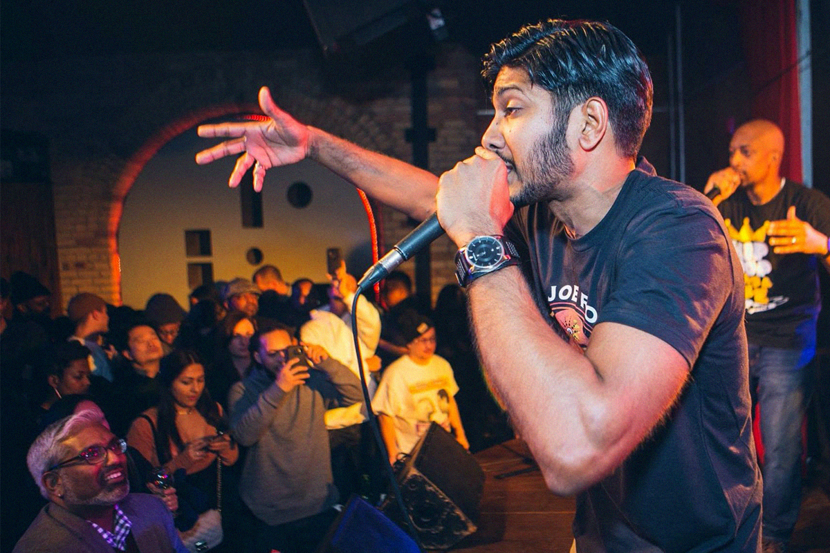 a person on stage rapping with a microphone in front of a crowd