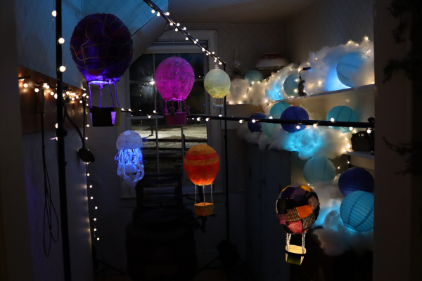 An installation of paper mache hot air balloons filled with multicoloured lights, suspended from poles in the Cornell House Pantry at Scarborough Museum.